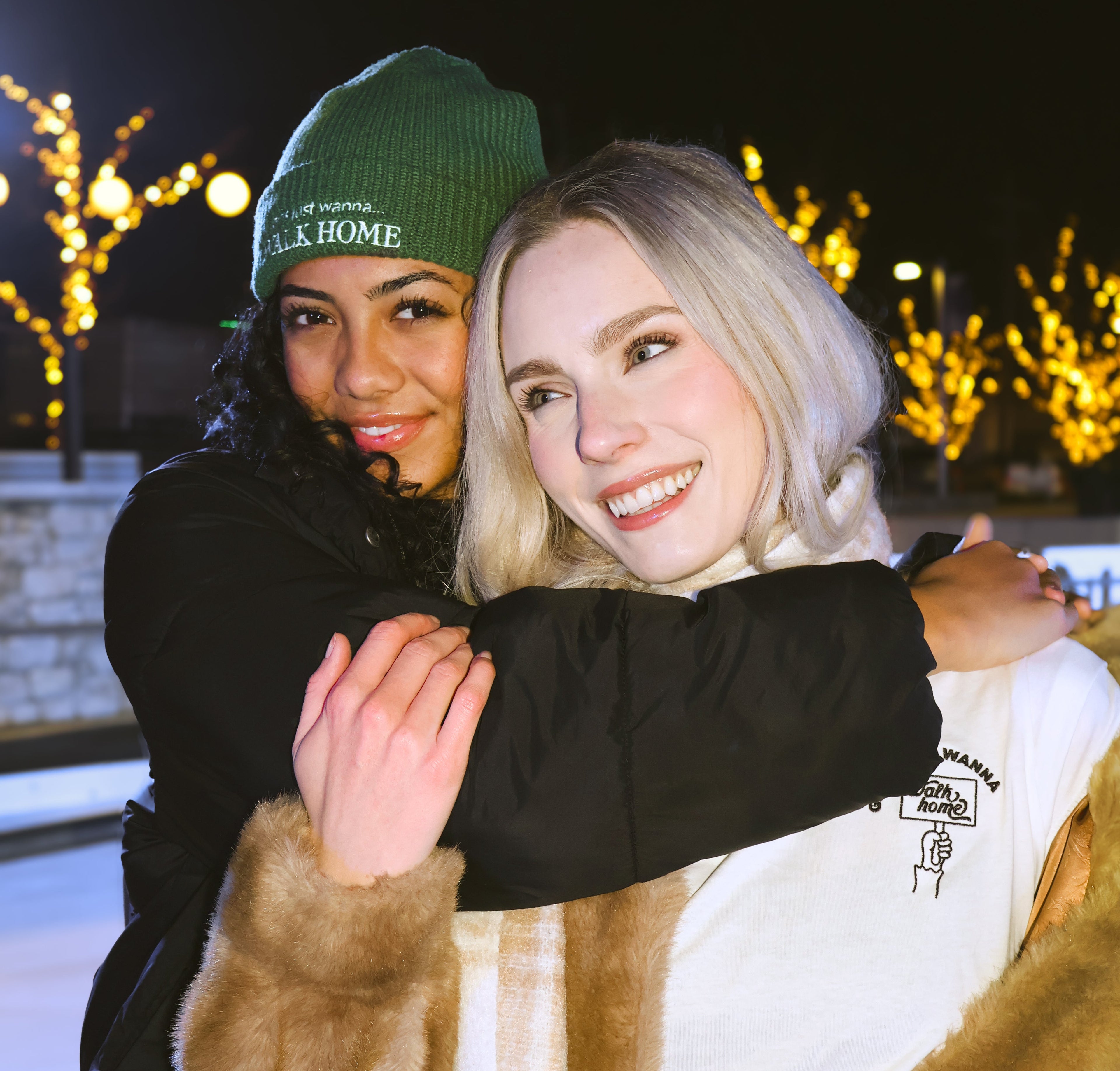 Two people hugging outdoors at night with decorative lights in the background